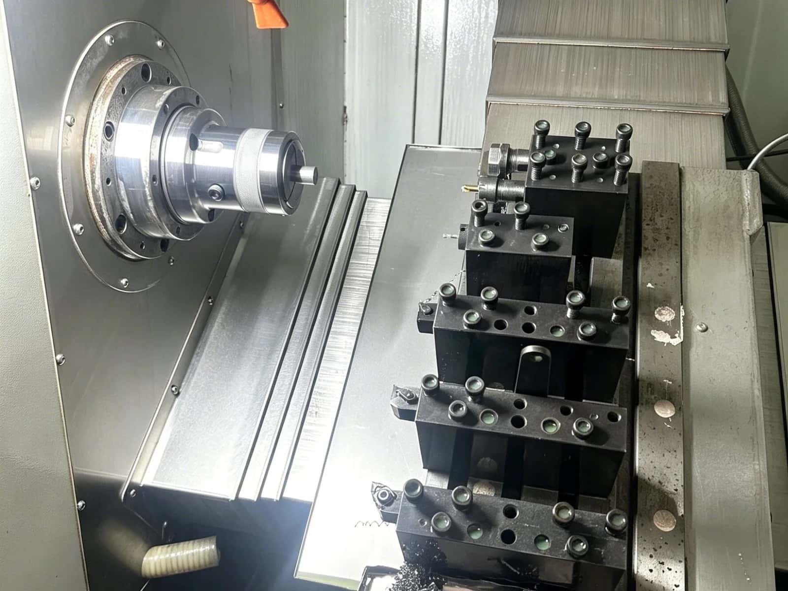 Swiss-style CNC lathe interior with spindle, gang tooling blocks, and coolant hose